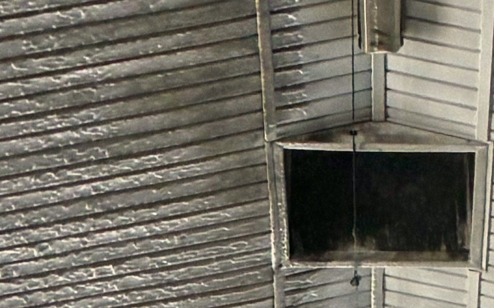 Dairy barn ceiling beside the ridge vent at 9:29 am, before washing: grey ribbed liner panels streaked with dust and residue.