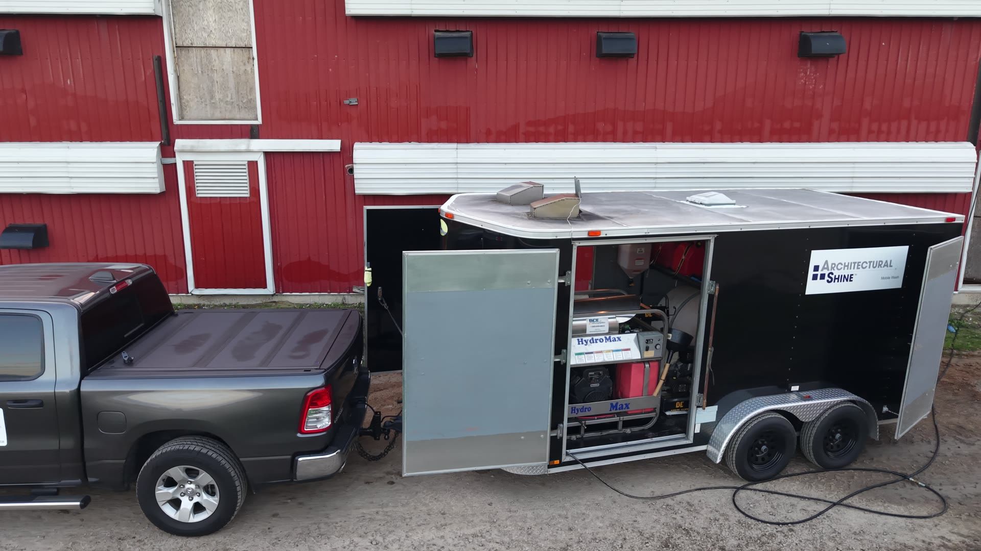 Our branded truck and wash trailer parked beside a red barn, seen from a drone